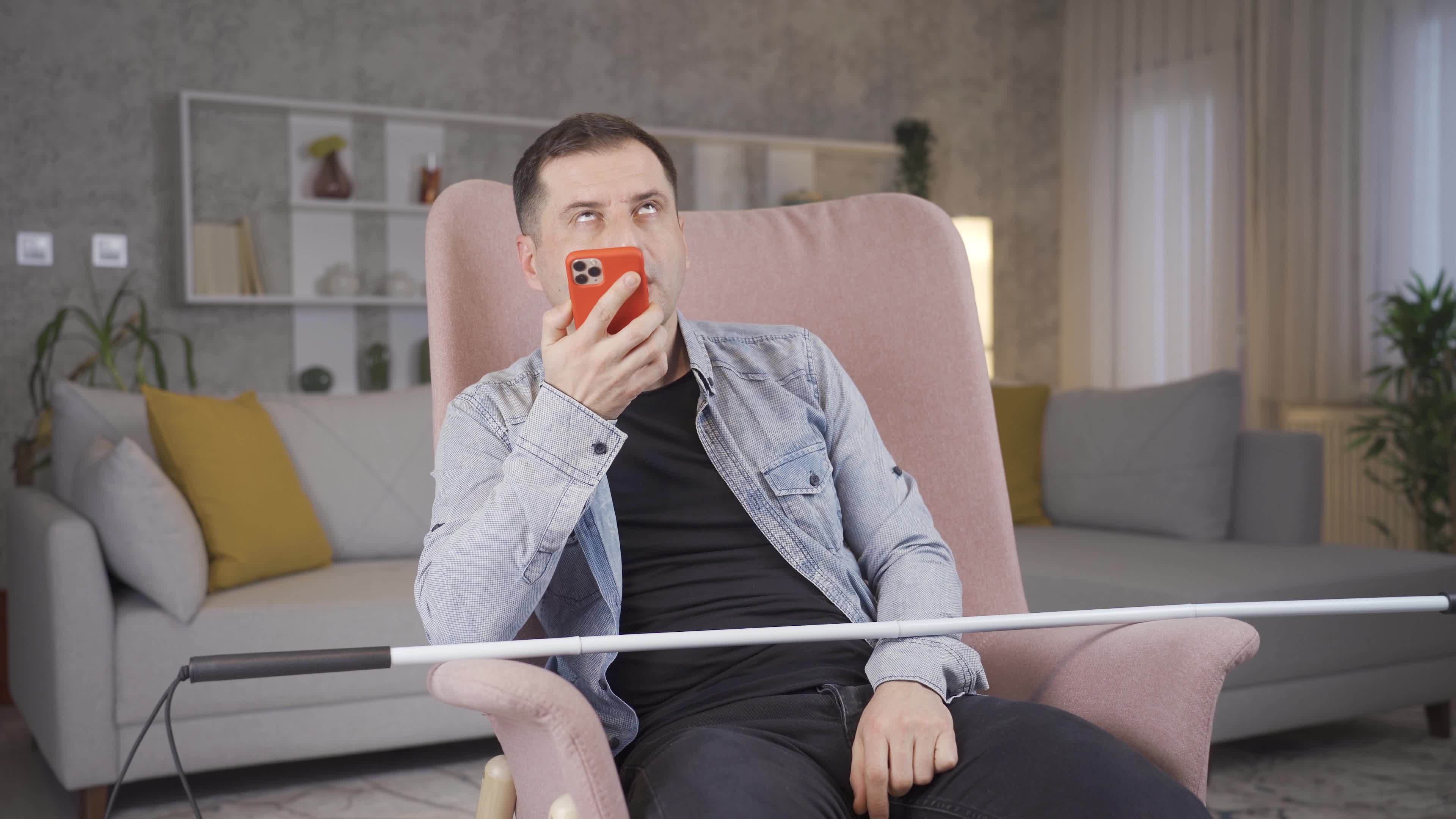 Blind man talking on the phone. Blind man sitting alone at home talking