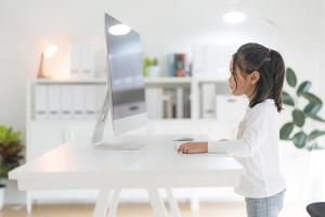 un niña utilizando un computadora teclado mientras. foto