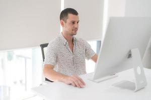 Young man using computer while sitting in chair. photo