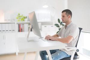 joven hombre utilizando computadora mientras sentado en silla. foto