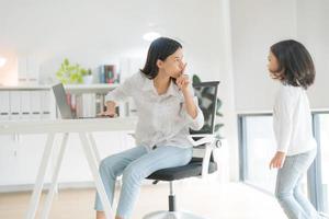 Mother trying to work at home office and daughter. photo