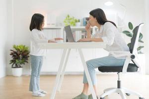 Mother trying to work at home office and daughter. photo