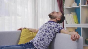 Happy and carefree man resting at home, relaxing and feeling peaceful. Happy and healthy man resting on sofa at home, enjoying comfort. video