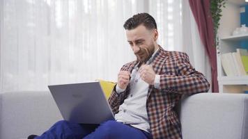 homem usando computador portátil regozija-se e é feliz. homem dentro terno é usando computador portátil às casa e alegria. video