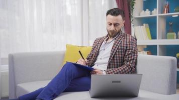 homem trabalhando com computador portátil às casa obtendo entediado e depressivo a partir de trabalhar. ocupado e sem parar homem usando computador portátil e obtendo cansado e estressado. video