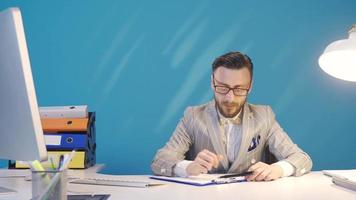 el aburrido empresario lo hace no querer a trabajo y es distraído. aburrido y reacio a trabajar, empresario gasta hora a su escritorio con otro elementos. video