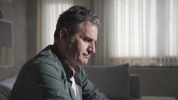 Home alone and sad man looking around thoughtfully. Mature man suffering from frustrated loneliness looks thoughtfully at home. video