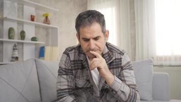 Close-up of lonely, thoughtful and unhappy man playing chess alone. Mature man sitting on sofa at home playing chess thoughtfully alone. video