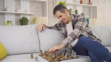 Lonely and unhappy calm mature gentleman playing chess alone at home. Thoughtful retired mature man playing chess at home alone executing strategy. video