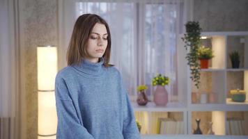 Unhappy and thoughtful young woman standing at home looking at camera and being serious. Thoughtful young woman looking at camera alone at home. video