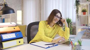 Business woman in glasses working remotely at home happy and satisfied working on laptop. Successful and confident young woman working on online business project and fulfilling her remote work task. video