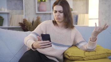 Young woman Using Smartphone Gets Sad and Surprised by Bad News. Surprised by Bad News, young woman feels disappointed at home.
