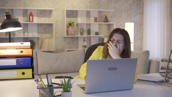 Tired business woman working from home at computer and falling asleep. Young business woman who works hard from home at night falls asleep at the table tired and devastated. video