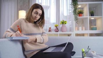 dotado menina usa computador portátil, escreve notas para estude para classe trabalho de casa. aluna menina é aprendizado, estudando para exames, usando computador portátil. artigo, composição, projeto atribuição. video