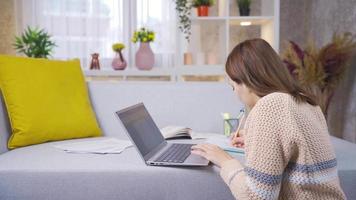 Young college student girl learning and learning remotely online using laptop. Talented Girl Uses Laptop, Writes Notes for Classwork Study. Using a laptop. Composition, project assignment. video