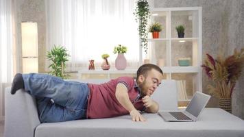 un' uomo con nanismo lavori a partire dal casa su un' il computer portatile. giovane uomo con nanismo è utilizzando il computer portatile a casa, contento e sorridente. video