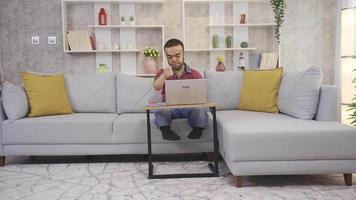 Jeune homme avec nanisme travail dans Accueil Bureau travail à distance en ligne avec portable et en pensant à propos le sien emploi, fabrication décision. video