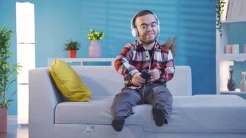 Happy disabled dwarf young man listening music with headphones having fun and holding dance beat. Young man with dwarfism listening to pleasant and entertaining music feels happy and peaceful at home. video