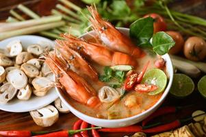 Hot and sour spicy shrimps prawns soup  curry lemon lime galangal red chili straw mushroom on table food, Shrimp soup on seafood soup bowl with thai herb and spices, Thai Food Tom Yum Kung photo