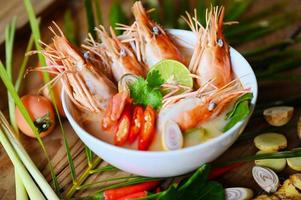 Hot and sour spicy shrimps prawns soup  curry lemon lime galangal red chili straw mushroom on table food, Shrimp soup on seafood soup bowl with thai herb and spices, Thai Food Tom Yum Kung photo