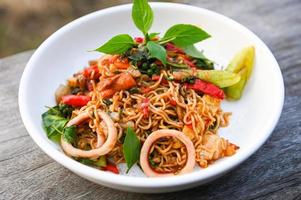 noodles plate with instant noodles stir fried with vegetables herb spicy tasty appetizing asian noodles mix seafood stir fried squid with basil and chilli pepper photo
