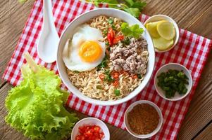 noodles bowl with boiled egg minced pork vegetable spring onion lemon lime lettuce celery and chili on table food , instant noodles cooking tasty eating with bowl - noodle soup photo