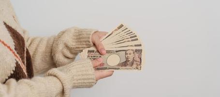 mano de mujer sosteniendo la pila de billetes de yen japonés. dinero de mil yenes. conceptos de pago en efectivo, impuestos, economía de recesión, inflación, inversión, finanzas y compras de japón foto