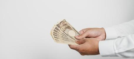 man hand holding Japanese Yen banknote stack. Thousand Yen money. Japan cash, Tax, Recession Economy, Inflation, Investment, finance and shopping payment concepts photo