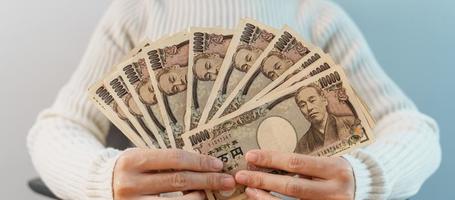 mano de mujer contando billetes de yenes japoneses sobre el fondo de la mesa. dinero de mil yenes. Japón efectivo, impuestos, economía de recesión, inflación, inversión, finanzas, ahorro, salarios y conceptos de pago foto