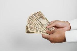 mano de hombre sosteniendo la pila de billetes de yen japonés. dinero de mil yenes. conceptos de pago en efectivo, impuestos, economía de recesión, inflación, inversión, finanzas y compras de japón