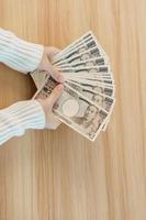 Woman hand counting Japanese Yen banknote over table background. Thousand Yen money. Japan cash, Tax, Recession Economy, Inflation, Investment, finance, savings, salary and payment concepts photo