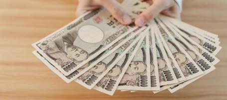 Woman hand counting Japanese Yen banknote over table background. Thousand Yen money. Japan cash, Tax, Recession Economy, Inflation, Investment, finance, savings, salary and payment concepts photo