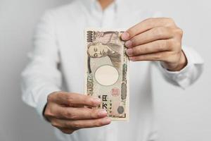 man hand holding Japanese Yen banknote stack. Thousand Yen money. Japan cash, Tax, Recession Economy, Inflation, Investment, finance and shopping payment concepts photo