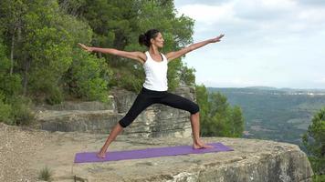 A female practicing yoga in a beautiful nature setting on top of a mountain at sunset video