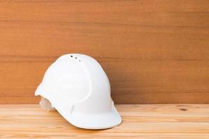 white safety helmet plastic construction of engineering on wood floor table background with copy space add text photo