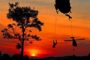 Silhouette Soldiers rappel down to attack from helicopter with sunset and copy space add text photo