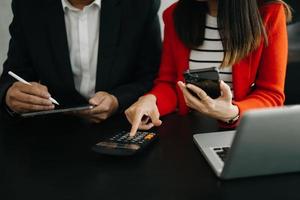 Business documents on office table with smart phone and calculator digital tablet and graph business with social network diagram and two colleagues discussing data working in the office photo