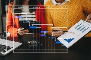 gerente de proyecto trabajando y actualizando tareas con hitos de planificación de progreso y diagrama de programación de diagramas de gantt. negocios que trabajan con teléfonos inteligentes, tabletas y computadoras portátiles en la oficina. foto