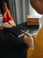 Woman's hand with cross .Concept of hope, faith, christianity, religion, church and pray to God. on the black table photo