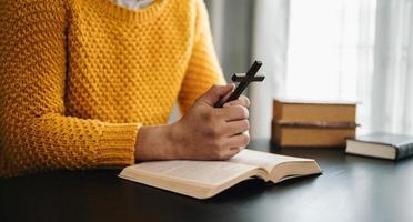 Hands together in prayer to God along with the bible In the Christian concept and religion, woman pray in the Bible on the wooden table photo