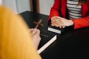 dos personas leyendo y estudiando la biblia en casa y rezando juntas. estudiando la palabra de dios con amigos. foto