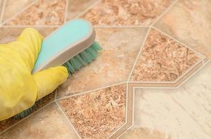 Man in yellow glove holds a brush for cleaning kitchen floor photo