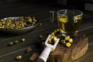 Chrysanthemum tea has flower dry on wood table top view. photo