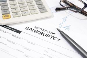 Bankruptcy form, calculator and pen on desk. Personal injury claim form photo