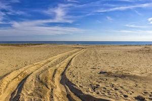 huellas de coche llantas en el arena de el mar playa. coche llantas huellas dactilares en mar arena durante el día foto