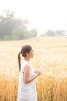 joven asiático mujer en blanco vestidos en el cebada arroz campo foto