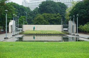 View of people watering the garden yard. This park is surrounded by greenery and several garden lampposts photo