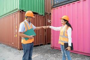 dos asiático industrial ingeniero hombre y mujer vistiendo la seguridad chaleco y casco. capataz hablando con trabajador o obrero en el industrial envase carga. foto