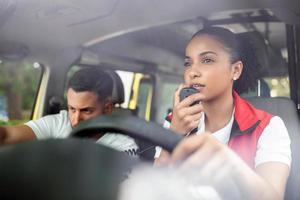 atractivo joven paramédico sentado en ambulancia y mirando lejos. joven mujer respondiendo un llamada en un ambulancia. ella es con su colega. foto