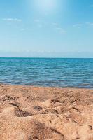 Beach with uneven sand and sea. Sun is shining, behind mountains. Vertical. Leisure, travel, vacation. Copy space photo